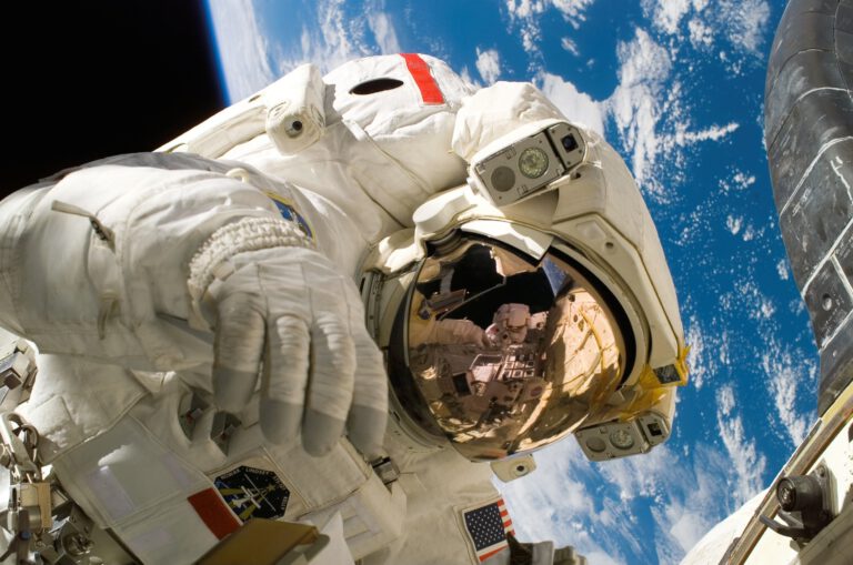 Astronauta w pełnym białym stroju kosmonauty, lewitujący w powietrzu na niebieskim tle