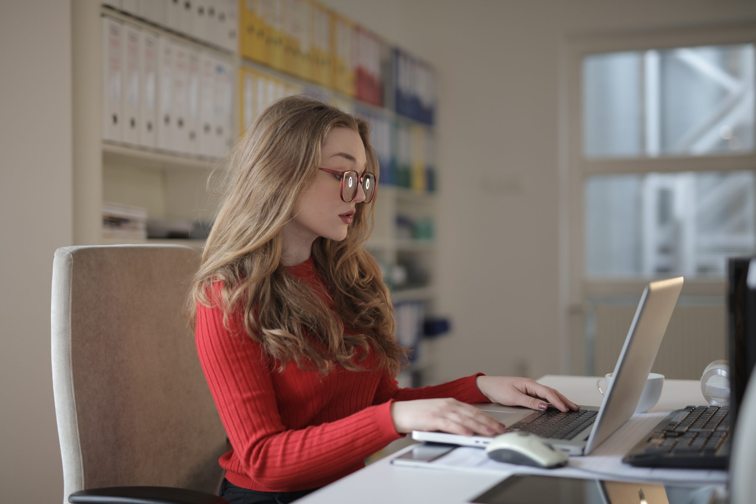 Młoda kobieta pracująca jako księgowa w biurze przed laptopem
