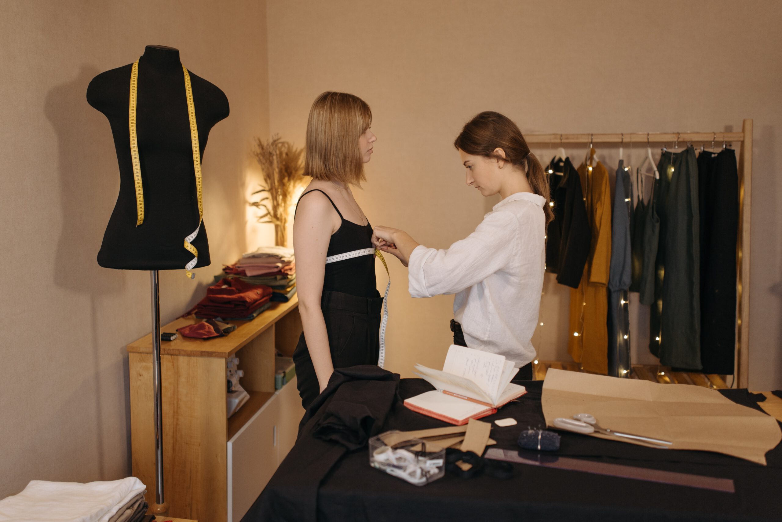 Projektantka mody w swojej pracowni podczas zdejmowania miary ze swojej modelki