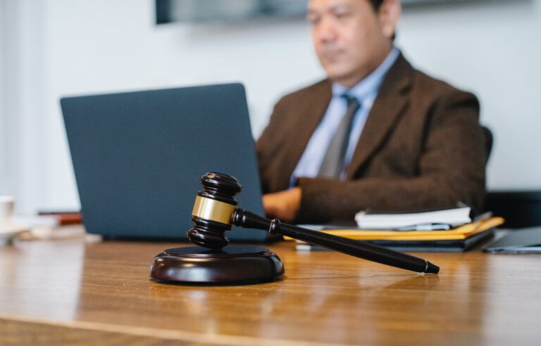 Prokurator podczas pracy na laptopie i młotek sędziowski na biurku