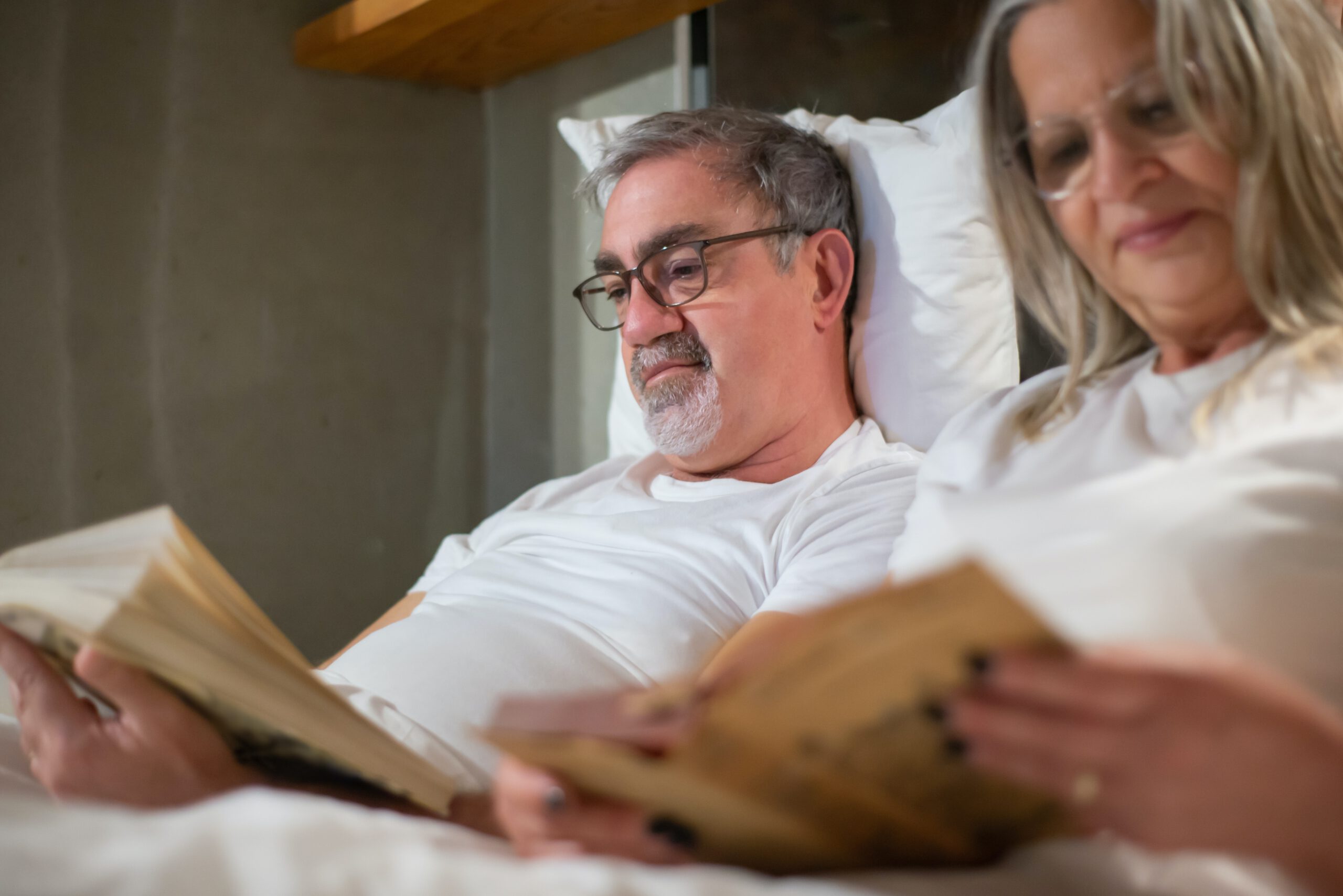 Starsze małżeństwo na emeryturze stażowej leżące w łóżku i czytające książki